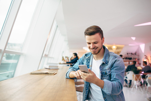 man looking at smartphone at bright cafe banquette