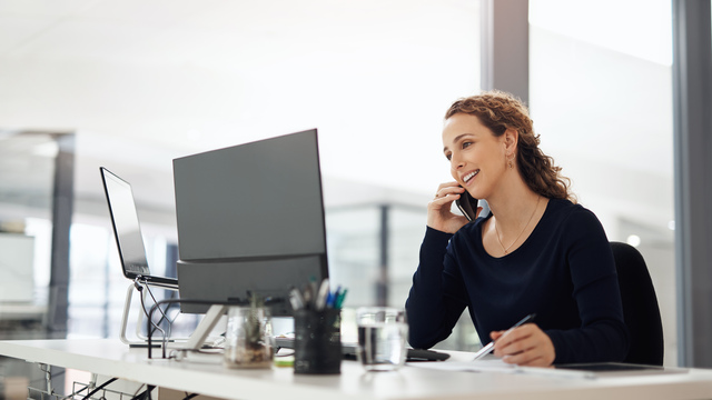 a medical provider on the phone at a desk in front of a computer. 