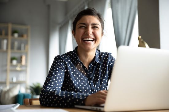 smiling woman working at computer sitting at desk looking into the camera