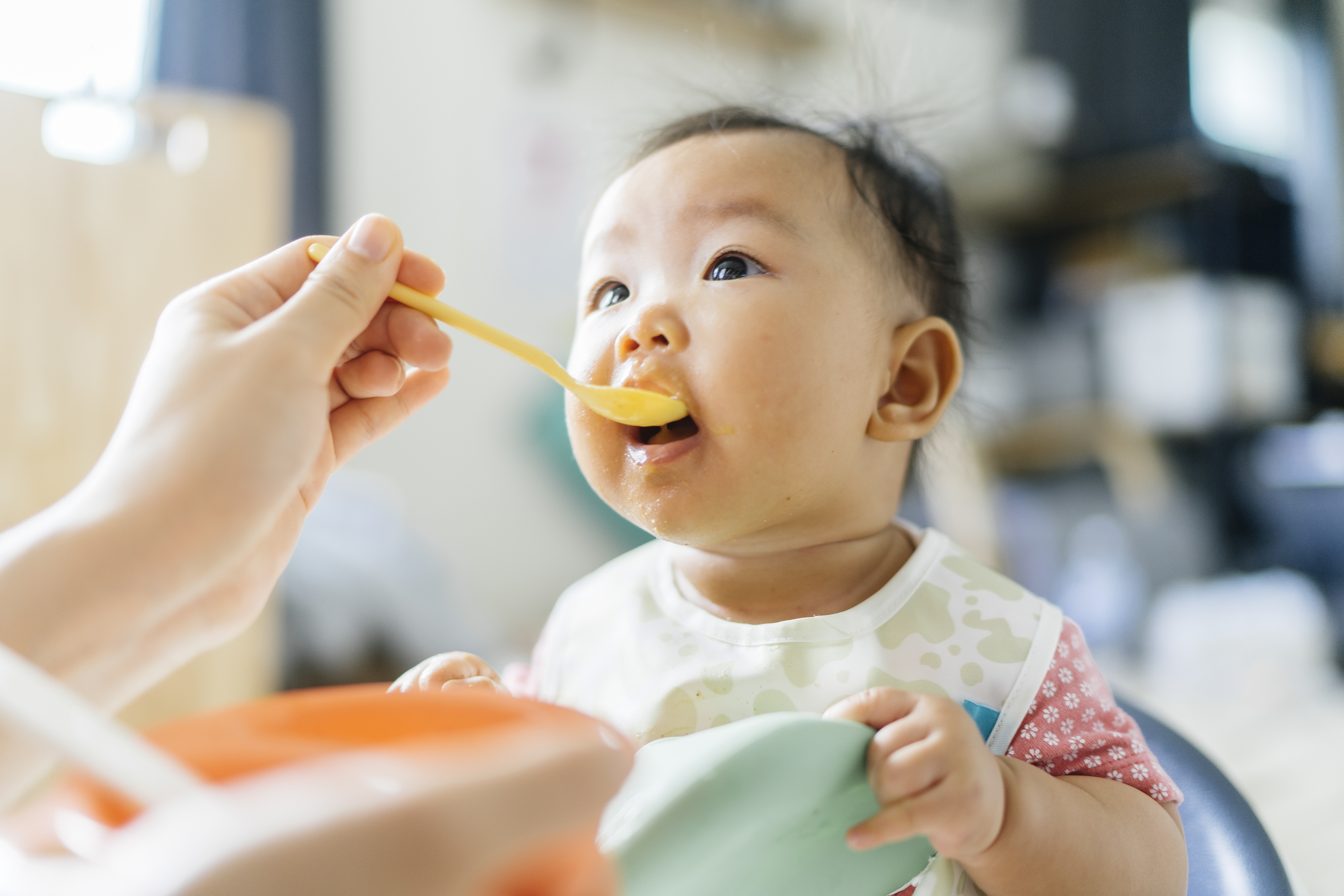 Baby sitting in chair being fed with a spoon