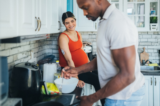 man cooking at stove for pregnant woman in the kitchen