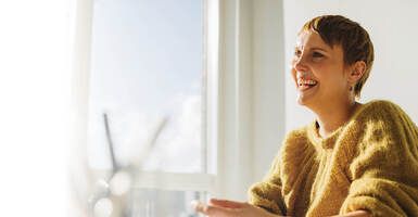 Smiling woman in yellow sweater sitting at table 