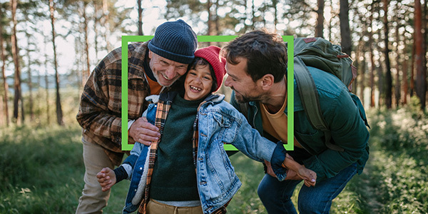 Grandpa, dad and son smilling while taking a hike outdoors