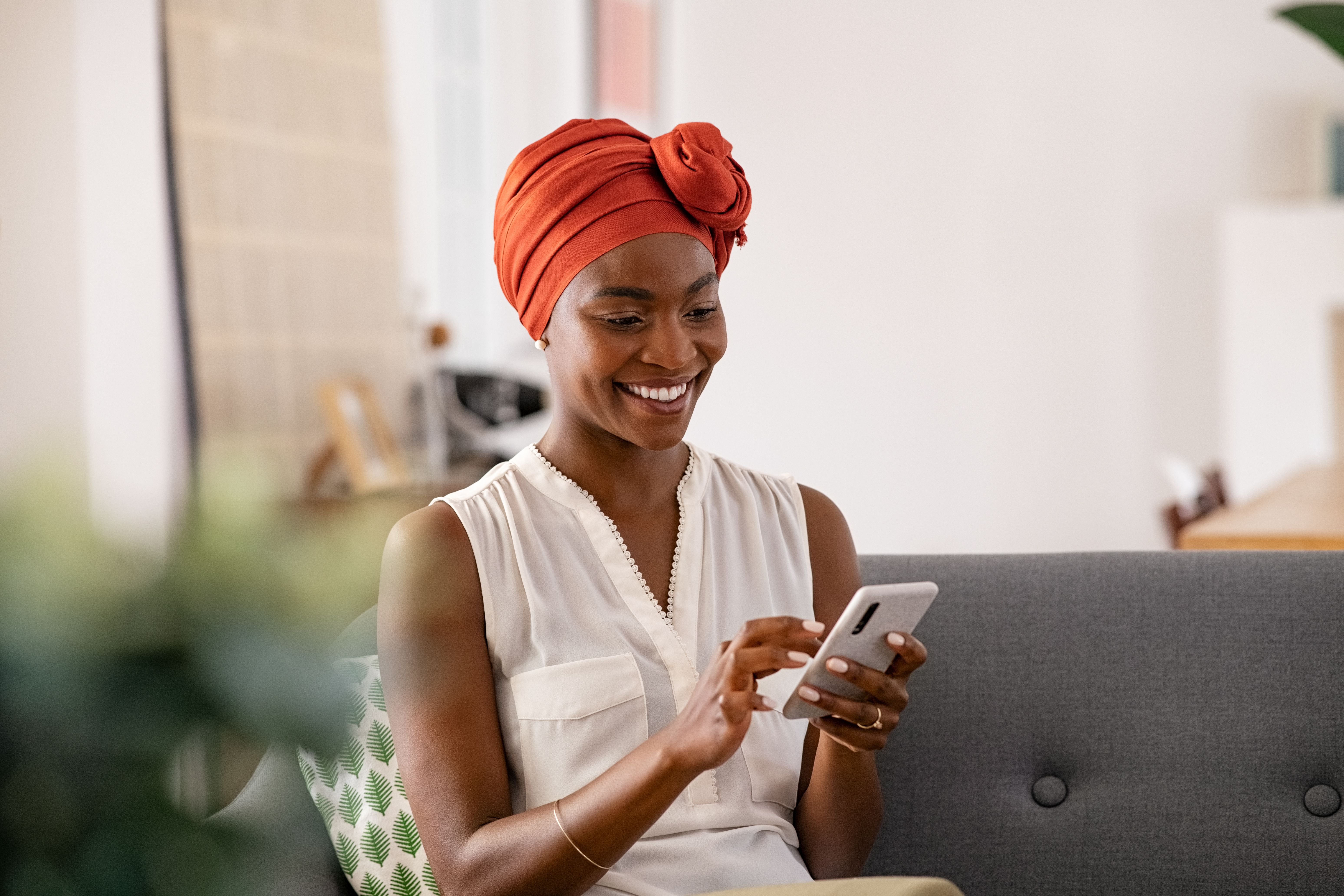woman sitting on couch smiling on phone