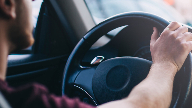 Man sitting in his car with his hand on the stearing wheel