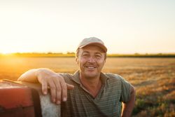 older man standing in field by his tractor