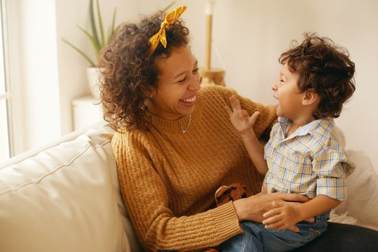 mom and son sitting on couch indoors smiling and laughing