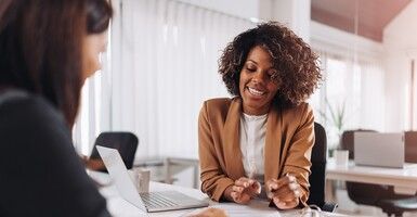 woman at desk helping another with paperwork