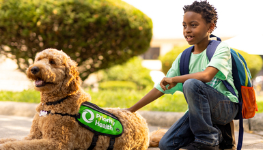 PriorityPups program featuring boy with visiting dog outside of a school