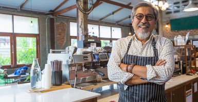 older smiling man working in coffee shop