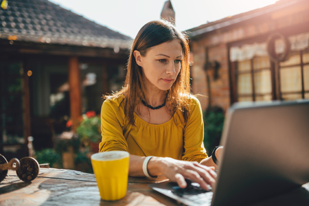 Woman working on a laptop outside in backyard garden