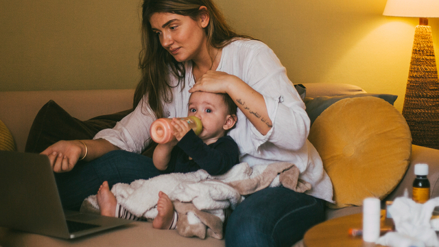 woman holding a toddler looking at laptop