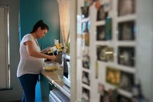 pregnant woman reading recipe instructions while mixing ingredients