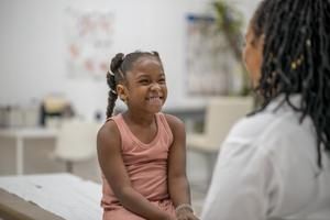 Child on physician's table smiling at doctor