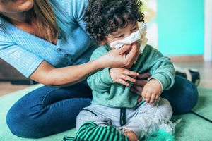 Dad holding sleeping infant to his shoulder in nursery