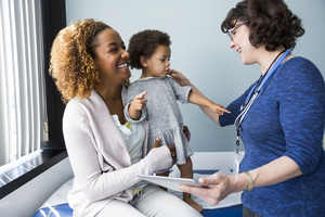 Mom holding toddler daughter while she gets examined at the doctor's office