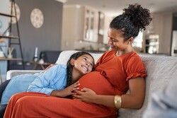 pregnant mother with her young daughter hugging mom's belly