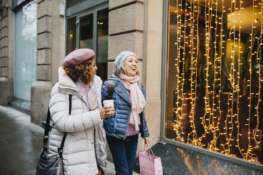 Two senior women walking down city street in winter