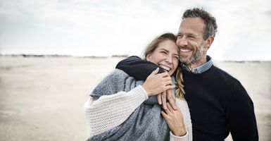 smiling middle age couple hugging on beach