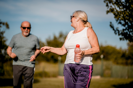 an older couple jogging outside in the sun