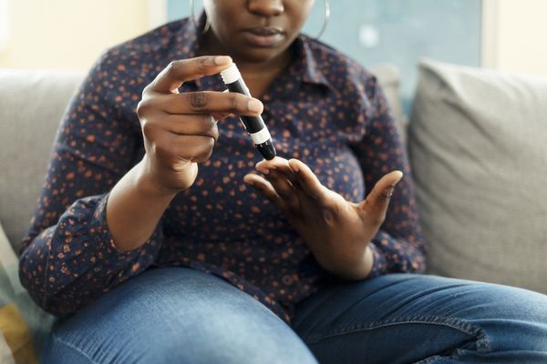 Woman sitting on couch checking blood sugar