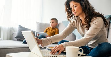 mom on laptop with son on couch