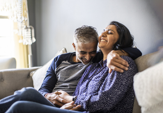 Man and woman holding hands and laughing on couch