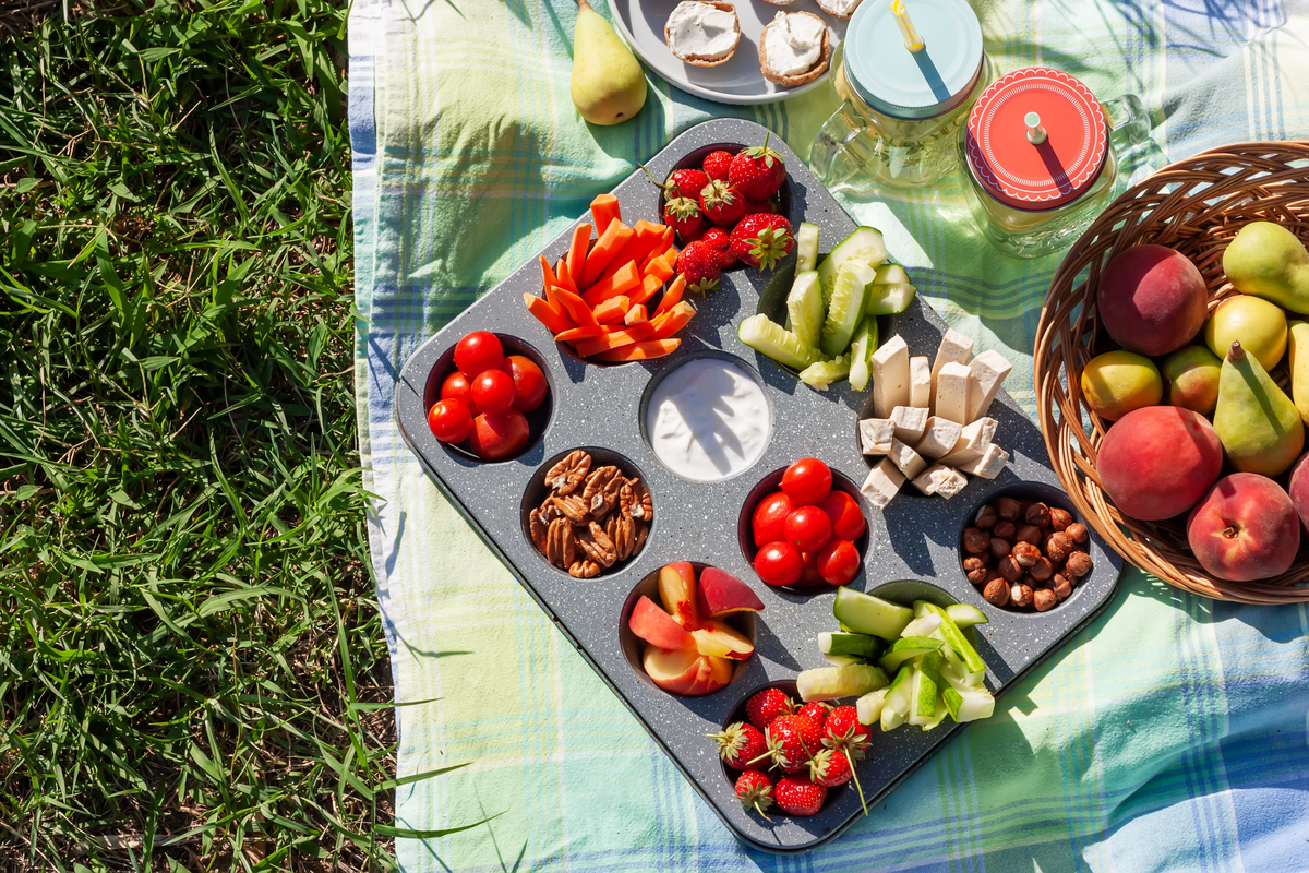 an array of healthy foods including fruits, vegetables, and nuts sitting on a picnic blanket in the grass