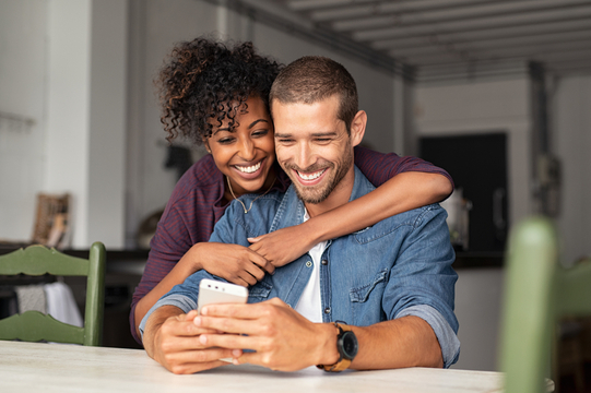 smiling young couple at a table looking at phone