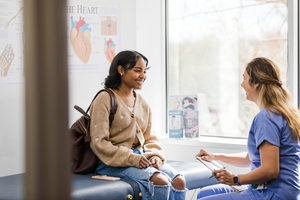 Health provider talking to a young woman in an exam room