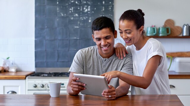 couple at home in their kitchen reviewing information on a tablet