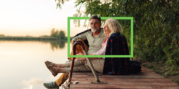 Older couple sitting on a dock and looking out at the sunset