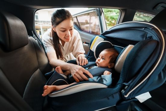 woman fastening her baby in a rear facing car seat