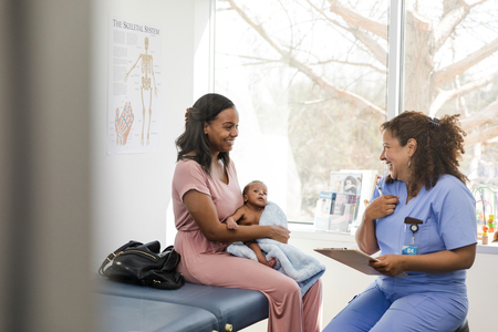 a woman holding an infant smiling at provider in a provider office