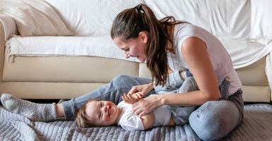 mom playing with smiling baby on the floor