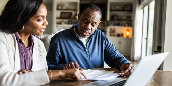 Couple sitting down reviewing documents and on a computer