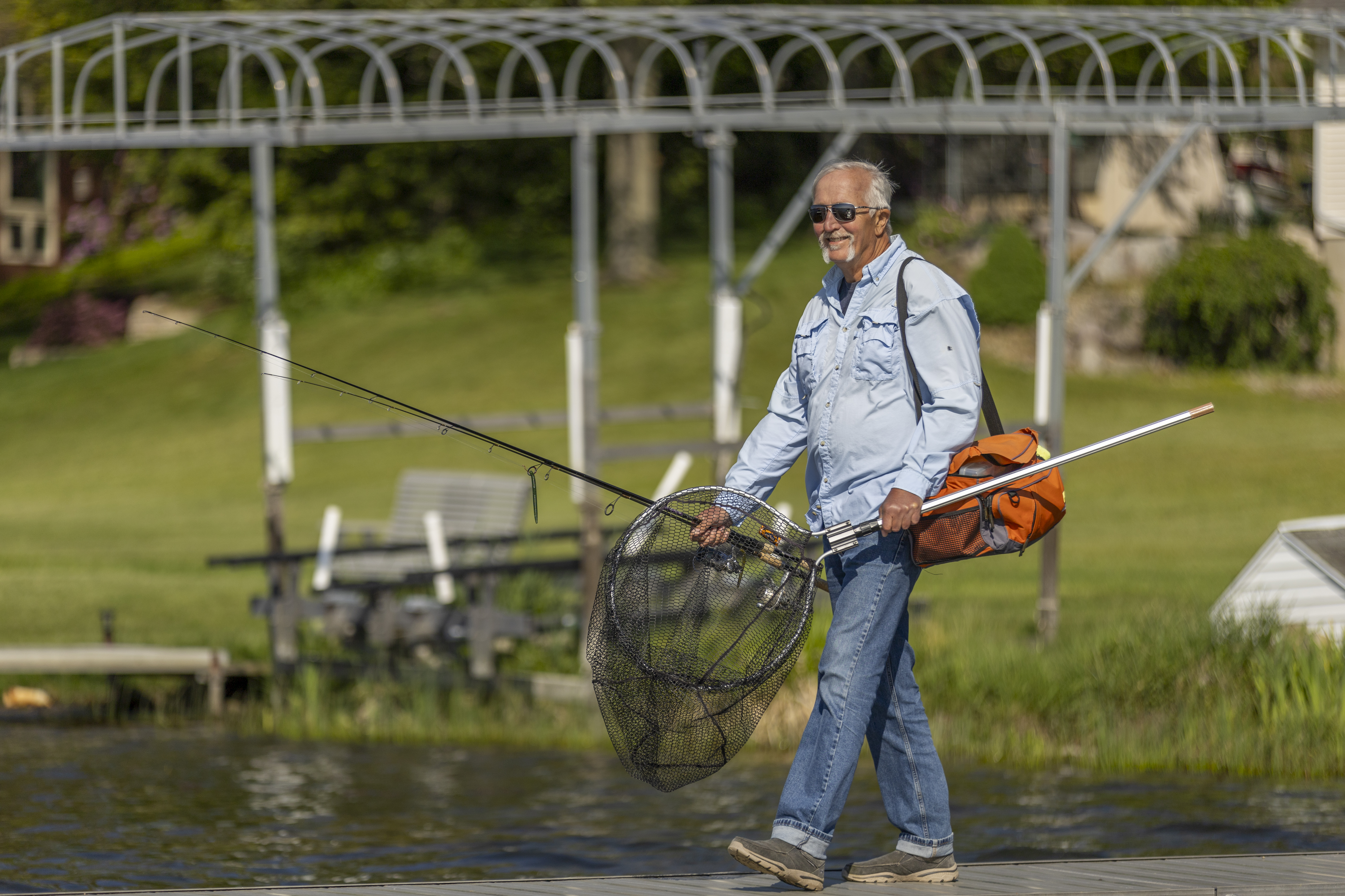Satch walking onto a dock holding fishing gear