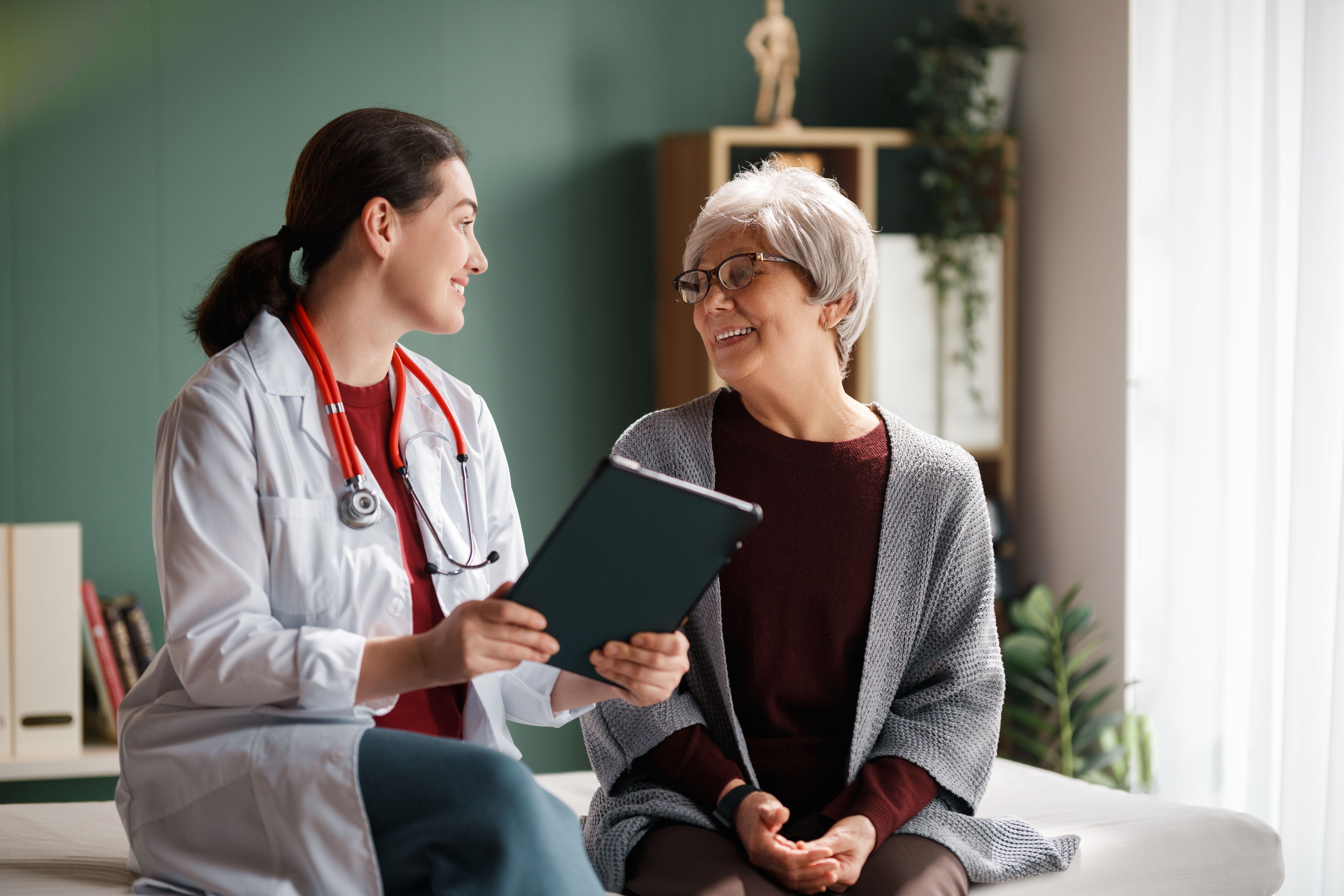 a young doctor consults an older female patient in her office