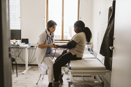 a doctor checking a woman's blood pressure in a provider office