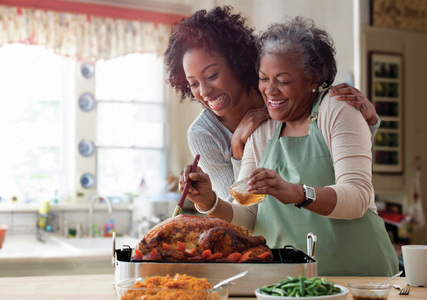 Adult daughter cooking happily with her elder mother