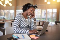 woman working on laptop with headphones in a public space