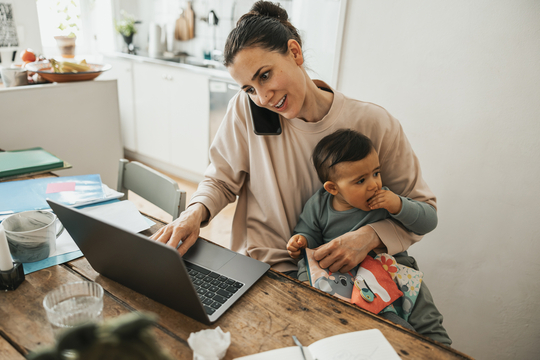 busy mom on laptop talking on the phone holding son