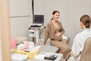 a pregnant patient talking in exam room with a medical provider.  