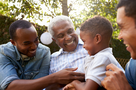 grandfather, father and sons sitting outside laughing and smiling