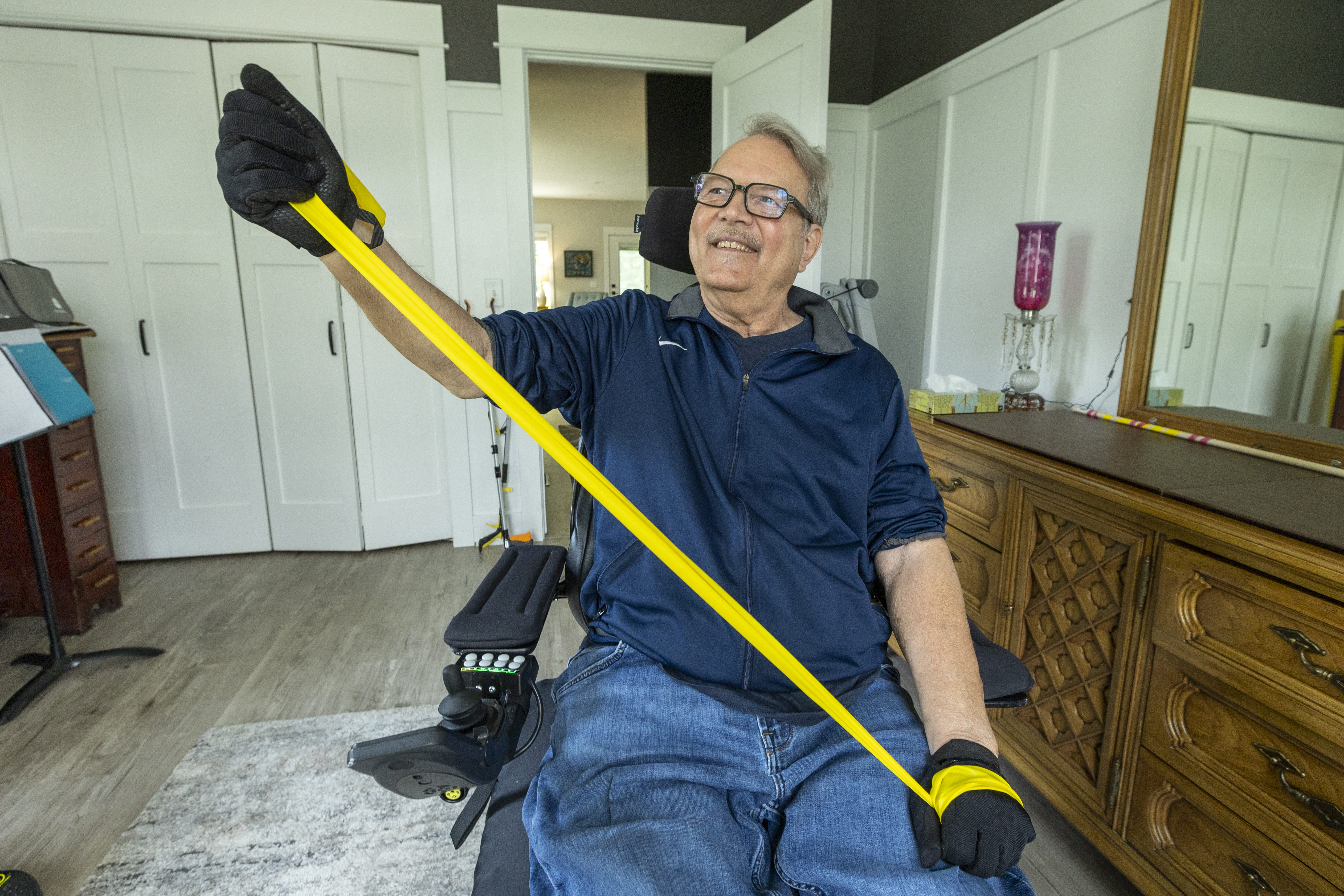 an older male in his wheelchair does physical therapy exercises with his arms and hands