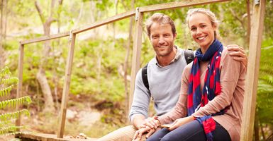 smiling couple sitting outside on wood bridge