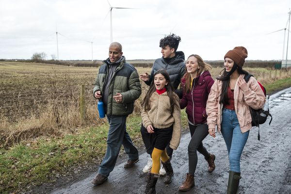 mom and dad with three kids walking in fall near farmland