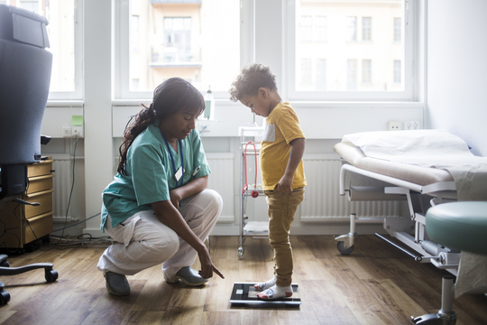 Nurse taking a young boys weight at the doctor office