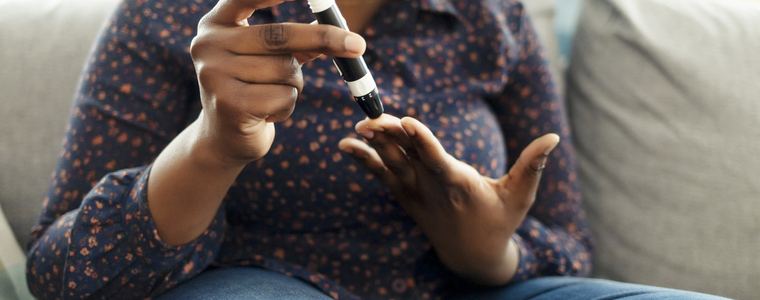 Woman sitting on couch checking blood sugar