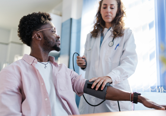 Health provider taking a young man's blood pressure